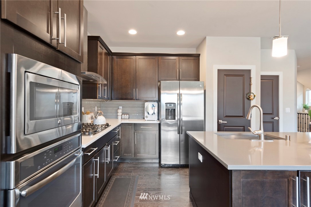 20619 3rd Avenue Southeast Bothell, WA 98012 - Photo 8 of 28 a kitchen with stainless steel appliances kitchen island granite countertop a sink refrigerator and cabinets