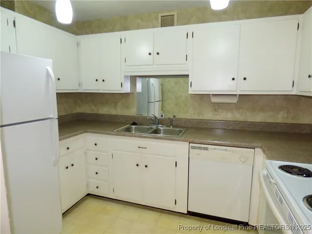 a kitchen with white cabinets and white appliances