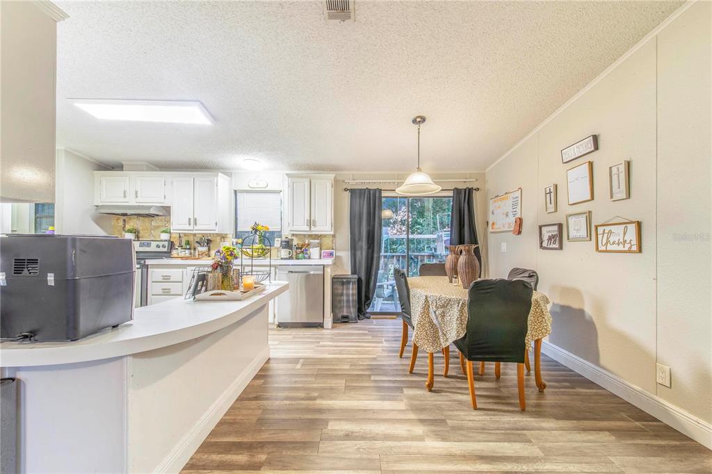2747 Old Bartow Road Lake Wales, FL 33859 - Photo 8 of 30 a dining room with stainless steel appliances kitchen island granite countertop a table chairs and a wooden cabinets
