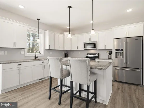 a kitchen with stainless steel appliances granite countertop a sink a stove a refrigerator and island with wooden floor