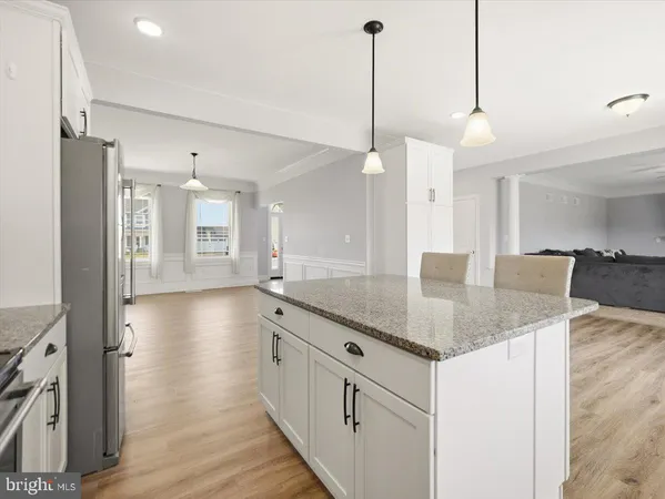 a kitchen with stainless steel appliances granite countertop a sink a center island and a wooden floor
