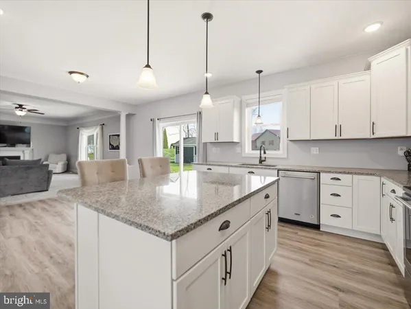a kitchen with stainless steel appliances granite countertop a sink a oven a dining table and chairs with wooden floor