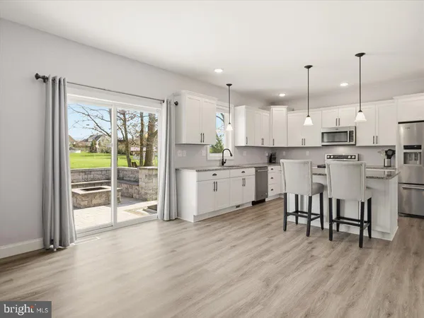 a kitchen with stainless steel appliances a table chairs refrigerator and cabinets
