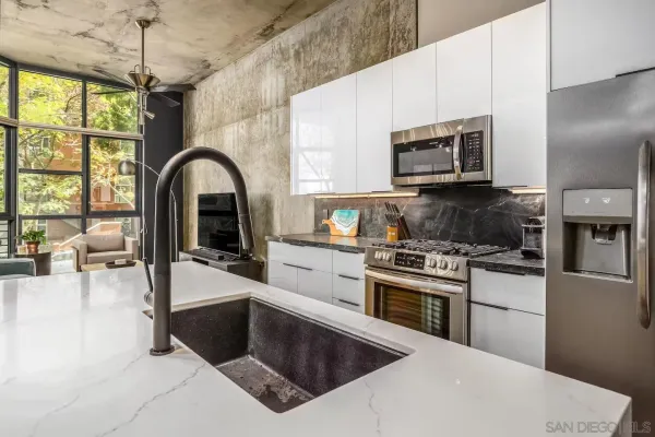 a kitchen with stainless steel appliances a stove a sink a microwave a dining table and chairs