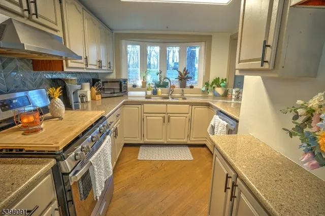 a kitchen with stainless steel appliances granite countertop a sink a stove and a wooden floors