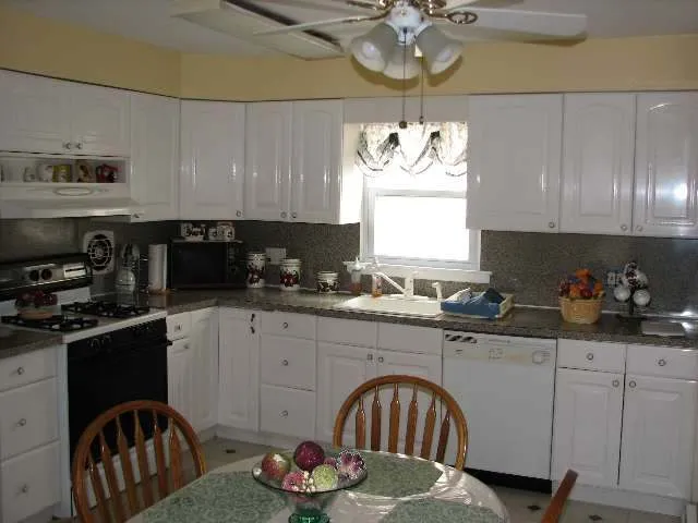 a kitchen with stainless steel appliances granite countertop a sink a stove a dining table and chairs with wooden floor