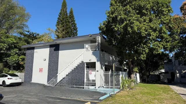 a view of a white house with a large tree