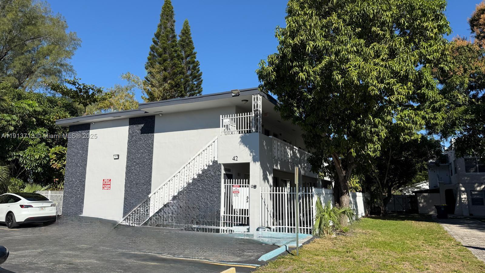 a view of a white house with a large tree