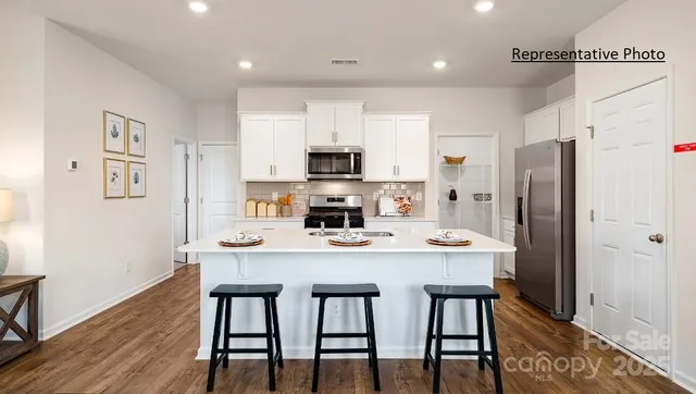 a kitchen with stainless steel appliances a table chairs refrigerator and microwave
