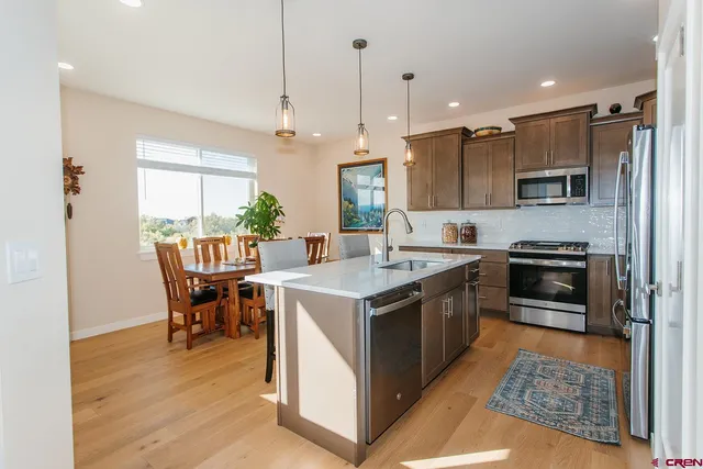 a kitchen with a stove a refrigerator and a dining table with wooden floor