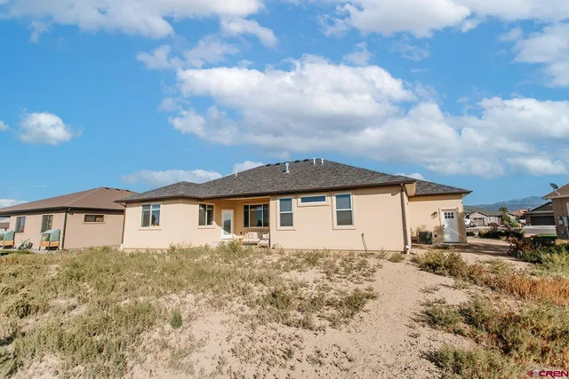 a view of a white house next to a yard with buildings