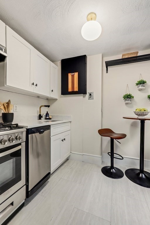 2 Goodwin Place, Unit 3 Boston, MA 02114 - Photo 12 of 28 a kitchen with stainless steel appliances a stove a refrigerator and a coffee table