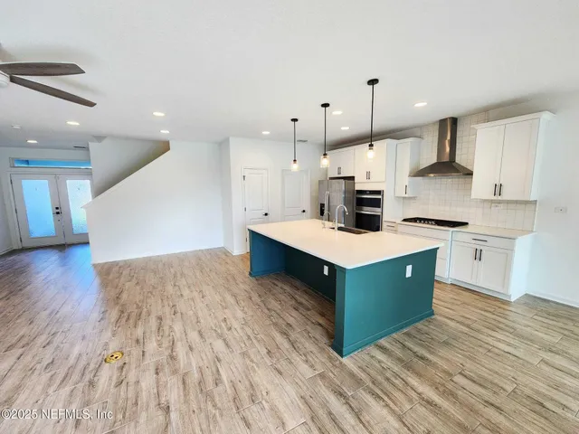 a large kitchen with stainless steel appliances a large counter top a stove a chimney a sink and a refrigerator