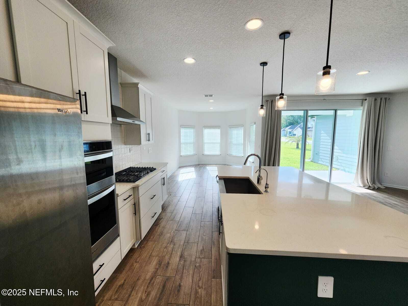 577 Archstone Way St. Augustine, FL 32092 - Photo 15 of 45 a large kitchen with stainless steel appliances a large counter top a stove a chimney a sink and a refrigerator
