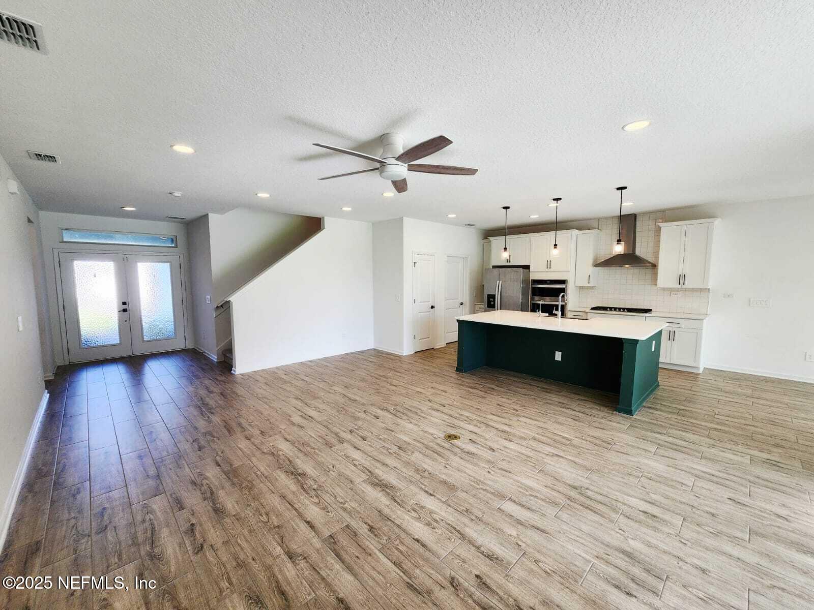577 Archstone Way St. Augustine, FL 32092 - Photo 7 of 45 a large kitchen with stainless steel appliances a large window a wooden floor and a kitchen island