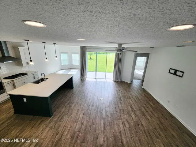 an empty room with wooden floor and a ceiling fan