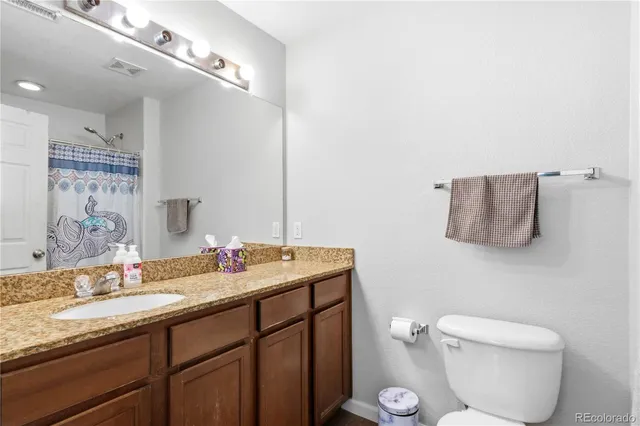 a bathroom with a granite countertop sink a toilet and a mirror