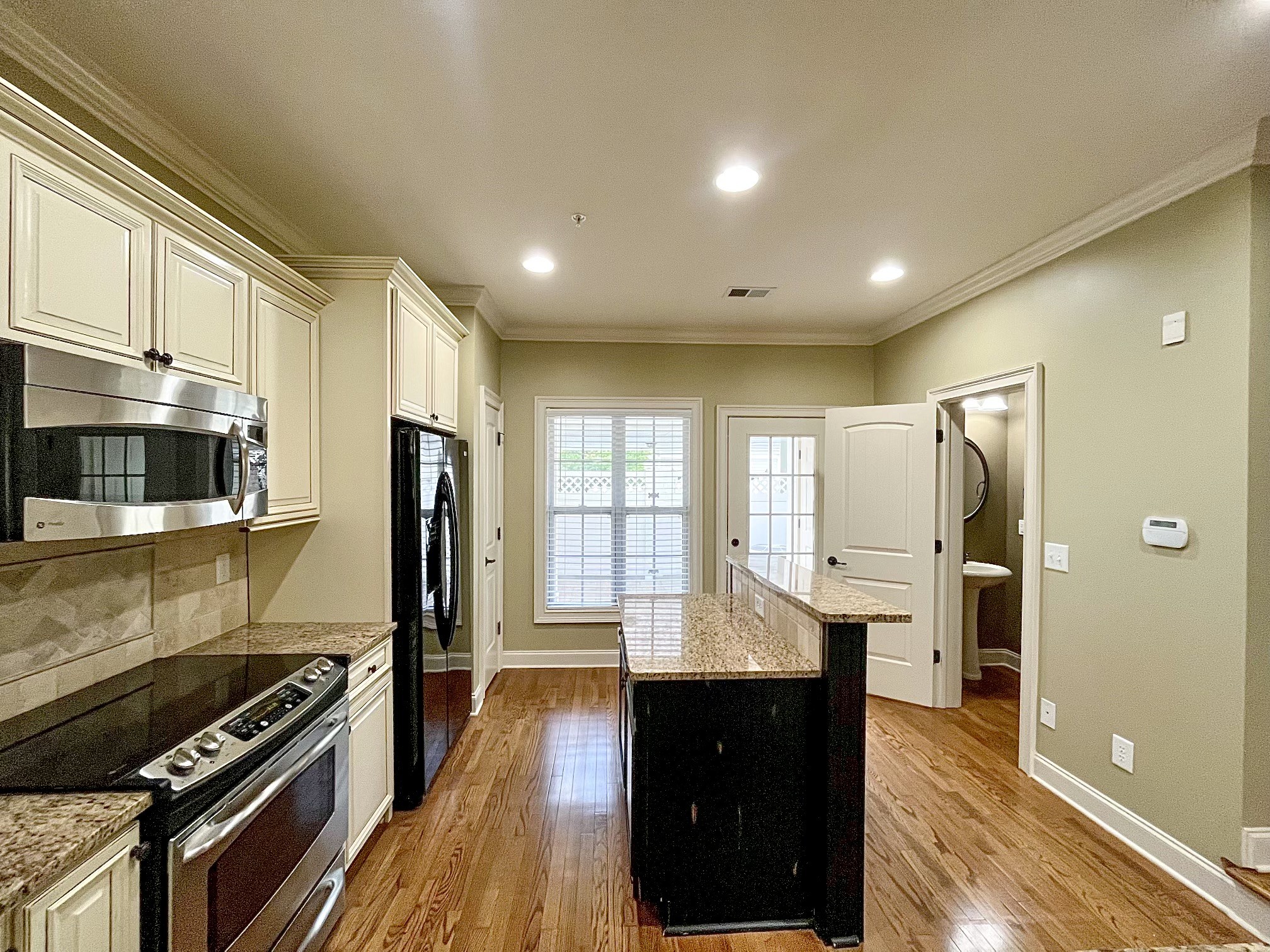4205 Prestwick Place Spring Hill, TN 37174 - Photo 3 of 12 a kitchen with stainless steel appliances a stove top oven a sink dishwasher a refrigerator and white cabinets with wooden floor