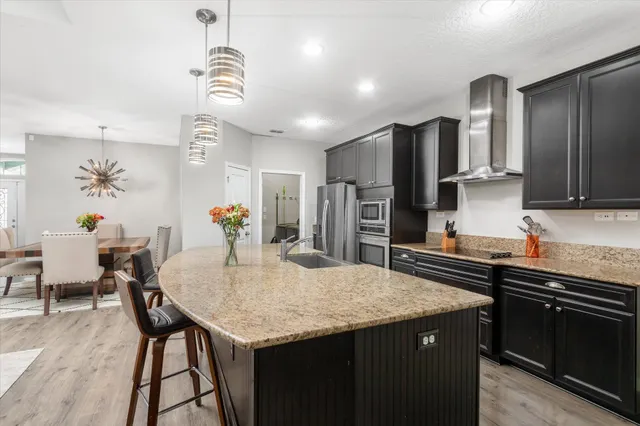 a kitchen with stainless steel appliances kitchen island granite countertop a kitchen island hardwood floor sink stove dining table and chairs