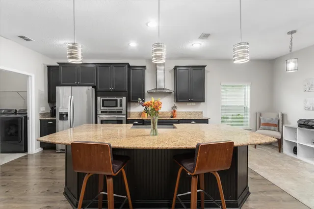 a kitchen with kitchen island granite countertop a table chairs stainless steel appliances and cabinets