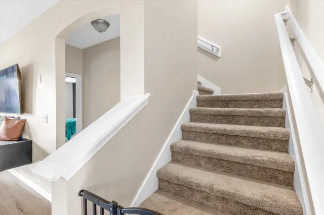 a view of staircase with white walls and a rug