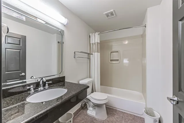 a bathroom with a granite countertop sink toilet a mirror and shower