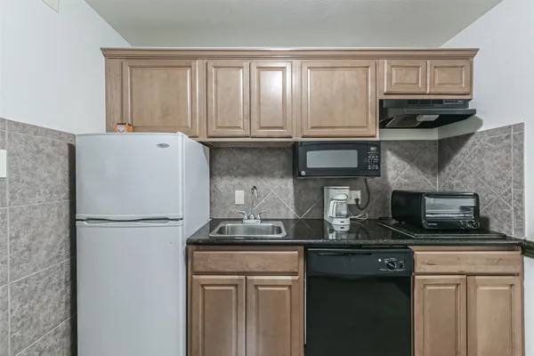 a kitchen with granite countertop a refrigerator a stove and a microwave