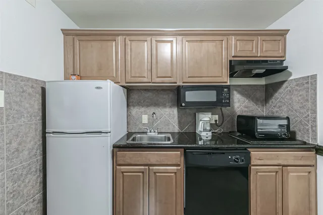 a kitchen with granite countertop a refrigerator a stove and a microwave