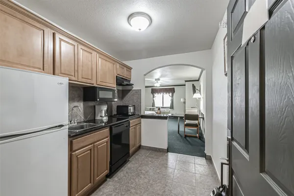 a kitchen with granite countertop stainless steel appliances a refrigerator stove top oven and sink