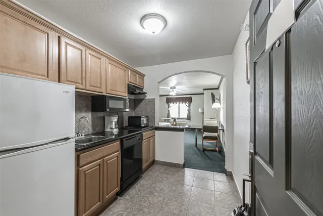 a kitchen with granite countertop stainless steel appliances a refrigerator stove top oven and sink