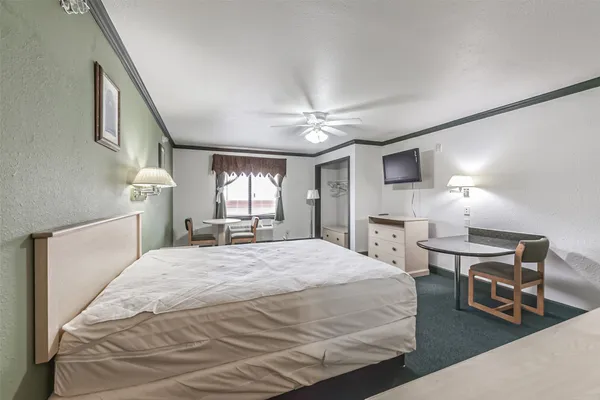 a spacious bedroom with a bed a chandelier furniture and windows