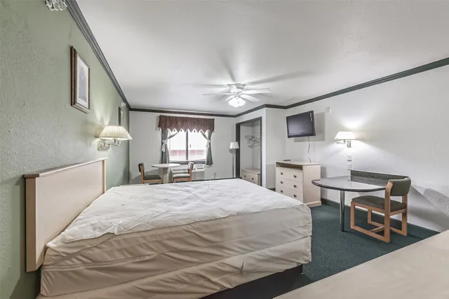 a spacious bedroom with a bed a chandelier furniture and windows