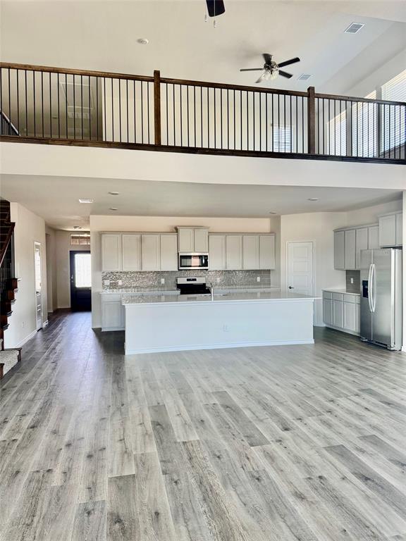 2408 Grapevine Way Celina, TX 75009 - Photo 19 of 20 Kitchen with stainless steel appliances, a large island with sink, a high ceiling, a ceiling fan, and open floor plan