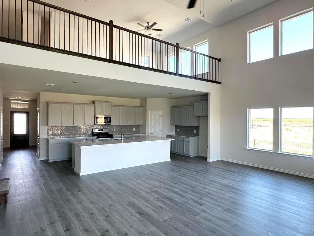 2408 Grapevine Way Celina, TX 75009 - Photo 20 of 20 Kitchen featuring gray cabinets, a center island with sink, a ceiling fan, open floor plan, and a high ceiling