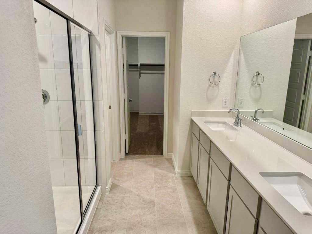 2408 Grapevine Way Celina, TX 75009 - Photo 8 of 20 Full bathroom featuring double vanity, a shower stall, a textured wall, and a walk in closet