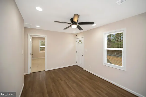a view of a room with wooden floor and ceiling fan