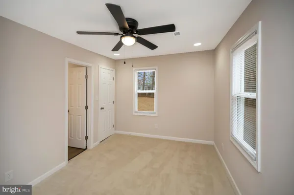 a view of a livingroom with a ceiling fan & windows