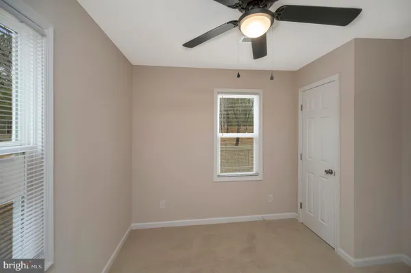 an empty room with a window and a chandelier fan