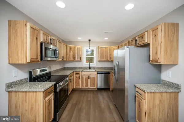 a kitchen with stainless steel appliances granite countertop a stove a refrigerator a sink dishwasher and wooden cabinets