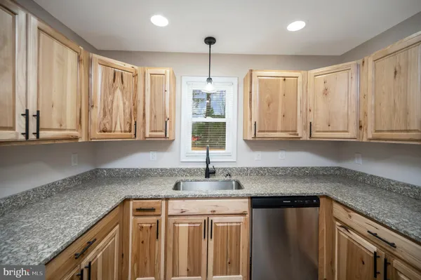a kitchen with granite countertop a sink stainless steel appliances white cabinets and a window