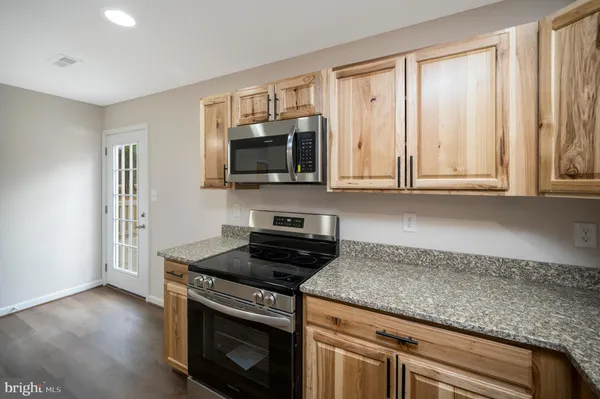 a kitchen with granite countertop a stove a sink and a microwave