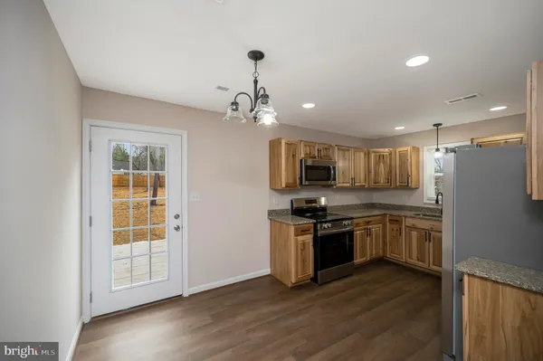 a kitchen with stainless steel appliances granite countertop a stove top oven a sink and a refrigerator