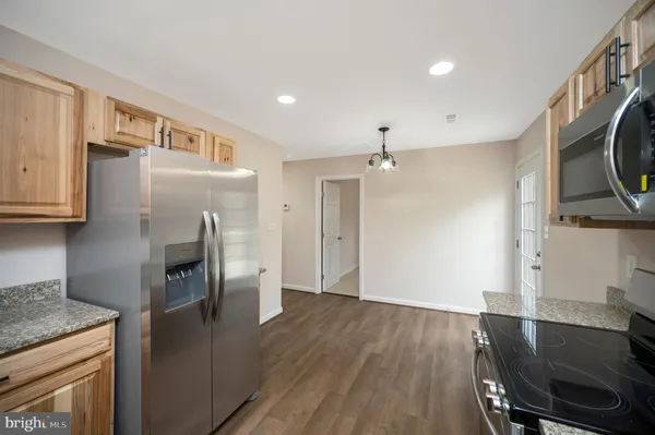 a kitchen with stainless steel appliances granite countertop a refrigerator a stove and a sink with wooden floor