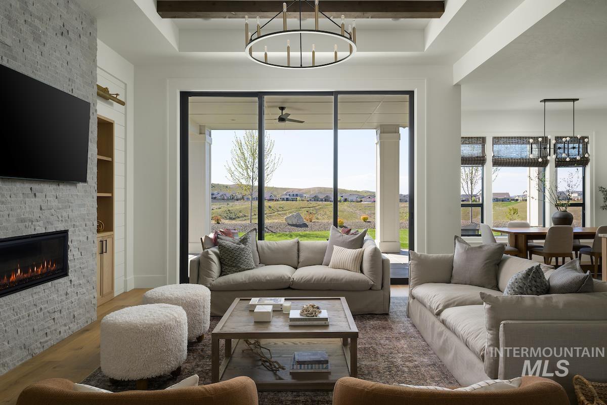 11415 North Misty Ridge Way Boise, ID 83714 - Photo 20 of 46 Living area featuring wood finished floors, a chandelier, a fireplace, a raised ceiling, and beamed ceiling