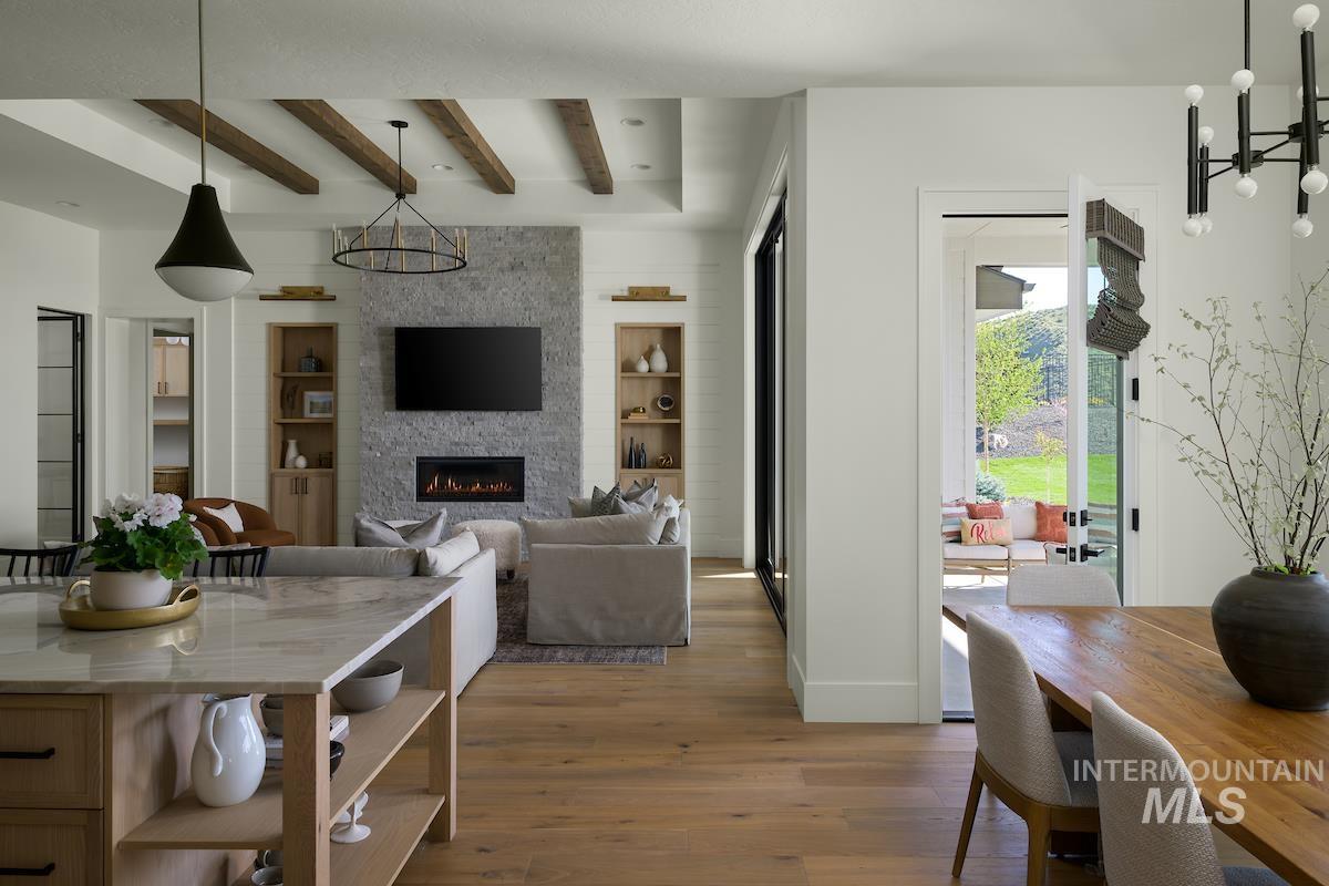11415 North Misty Ridge Way Boise, ID 83714 - Photo 24 of 46 Dining space featuring wood finished floors, beamed ceiling, built in features, a large fireplace, and a chandelier