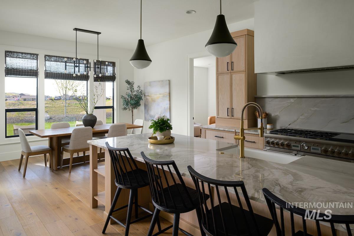 11415 North Misty Ridge Way Boise, ID 83714 - Photo 26 of 46 Kitchen with light brown cabinets, high end range, light stone countertops, a kitchen bar, and light wood-style flooring