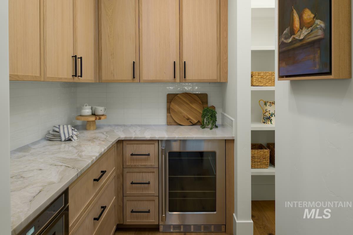 11415 North Misty Ridge Way Boise, ID 83714 - Photo 27 of 46 Kitchen featuring beverage cooler, light stone counters, decorative backsplash, and wood finished floors