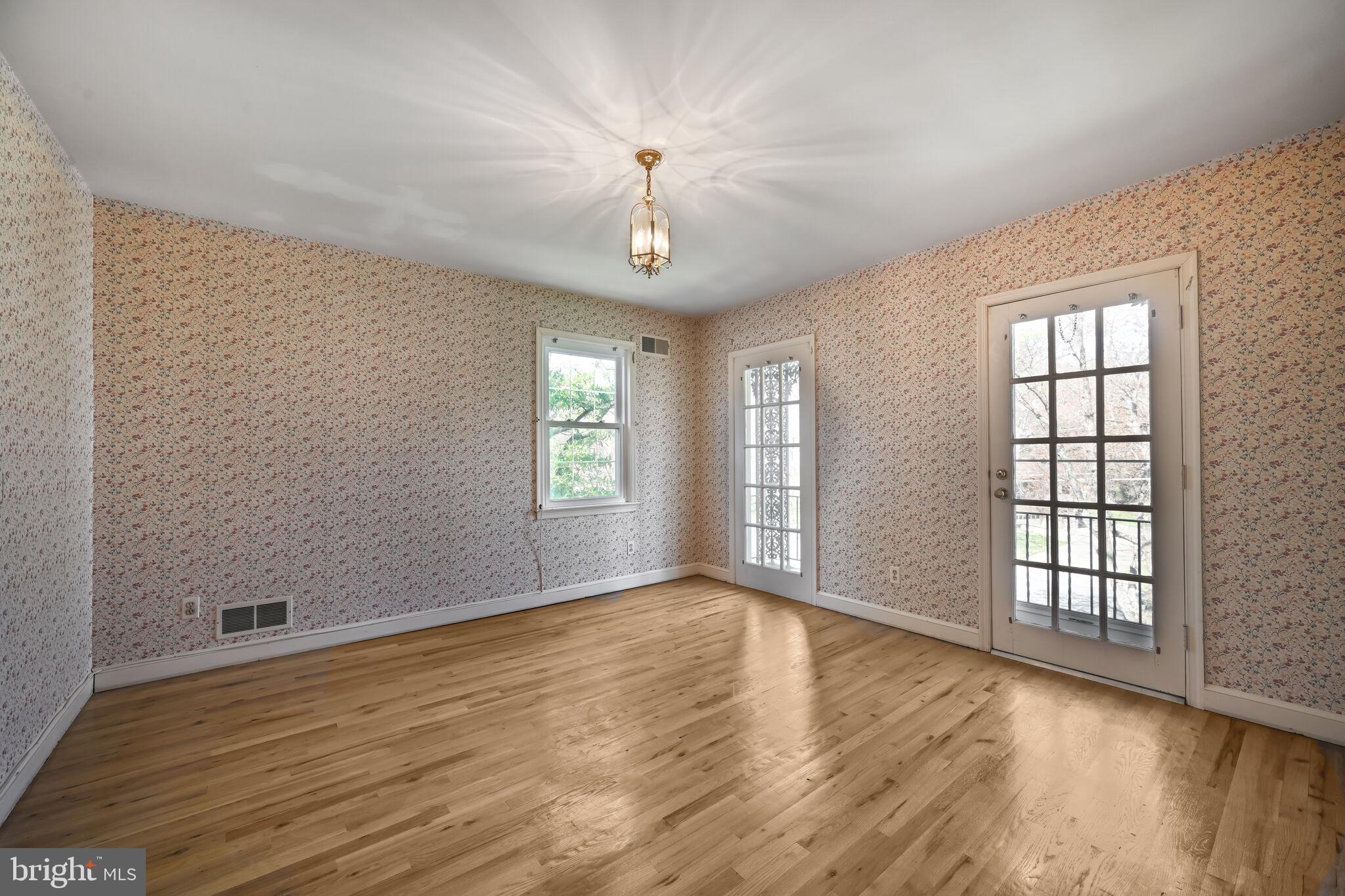 11337 Willowbrook Drive Rockville, MD 20854 - Photo 22 of 50 an empty room with wooden floor chandelier and windows