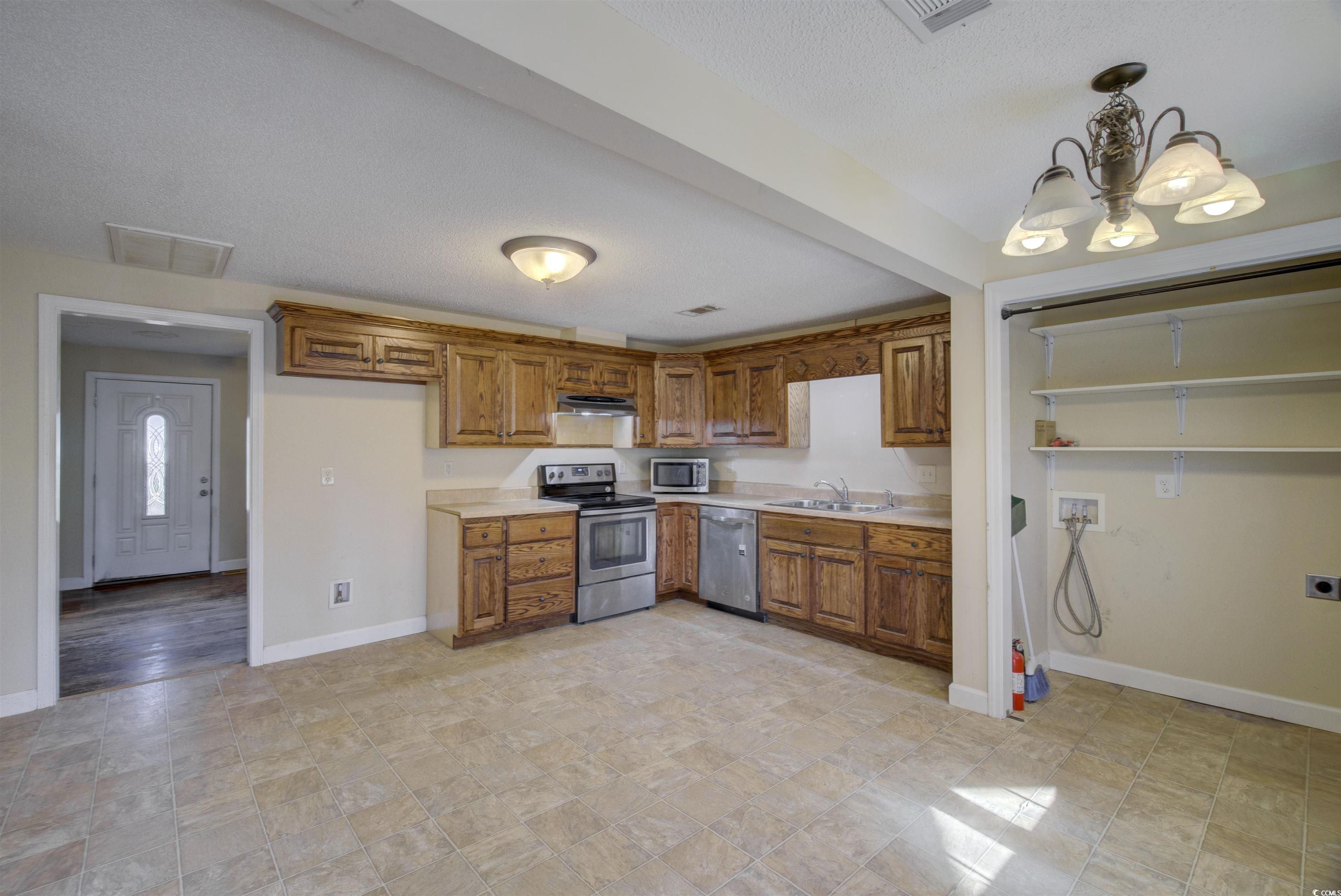 2080 Highway 90 Conway, SC 29526 - Photo 9 of 29 Kitchen with brown cabinetry, light countertops, stainless steel appliances, hanging light fixtures, and a chandelier