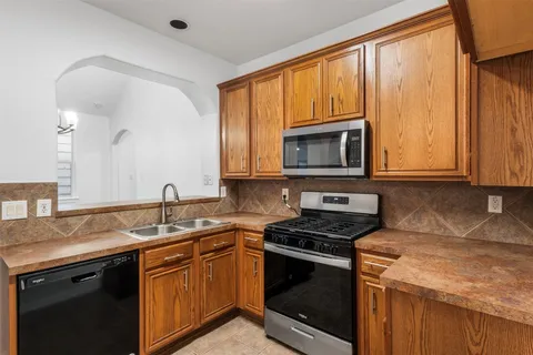 a kitchen with granite countertop wooden cabinets stainless steel appliances and a sink